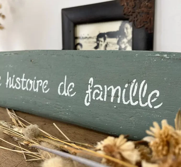 pancarte en bois flotté peinte couleur vert de gris. L'île d'Yeu une histoire de famille. Fleurs séchées posées sur établi en bois
