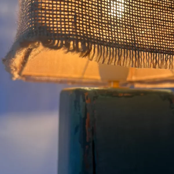 gros plan d'une lampe allumée. Abat jour en jute laissant filtrer la lumière