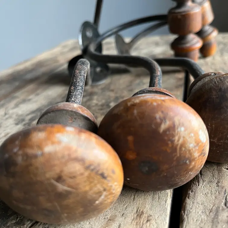 Gros plan de patères anciennes en bois de 1900 posées sur un établi ancien