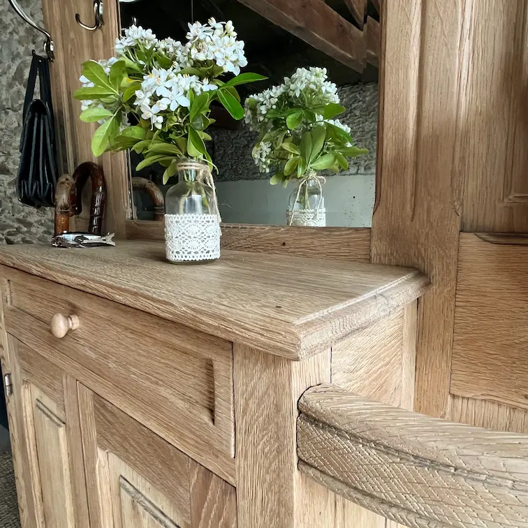 Vestiaire ancien en chêne rénové. Gros plan sur le dessus du meuble de rangement. Bouquet de fleurs blanches posé dessus.