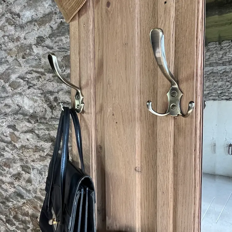 Vestiaire ancien en chêne rénové. Gros plan sur les patères en laiton