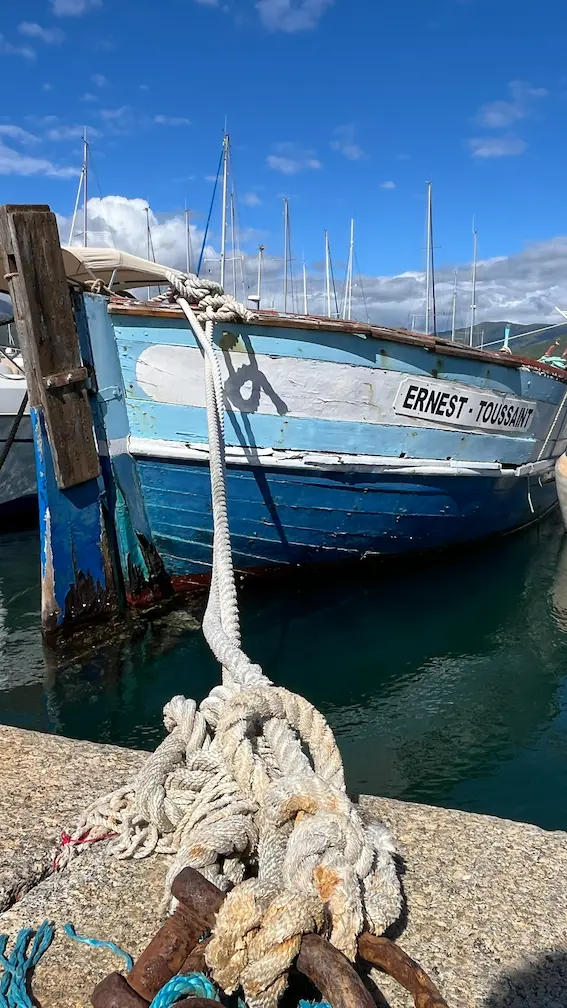 coque de bateau bleu amarrée au port de Porto Vecchio en Corse. Corde et anneau d'amarrage au premier plan