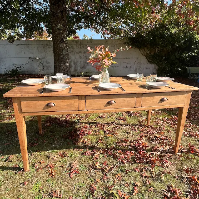 table de ferme présentée avec de la vaisselle ancienne dans le jardin