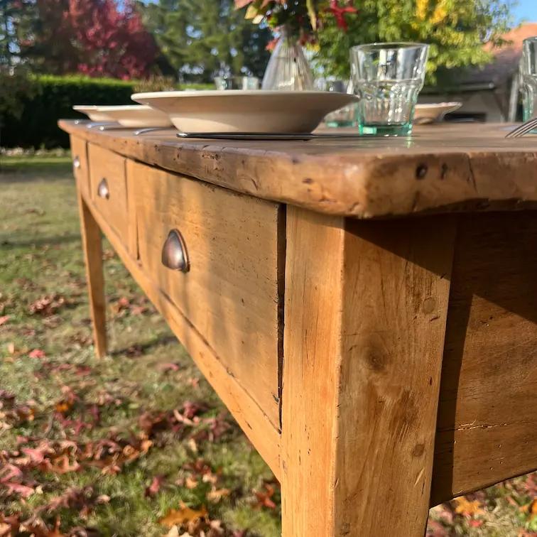 table de ferme présentée avec de la vaisselle ancienne dans le jardin