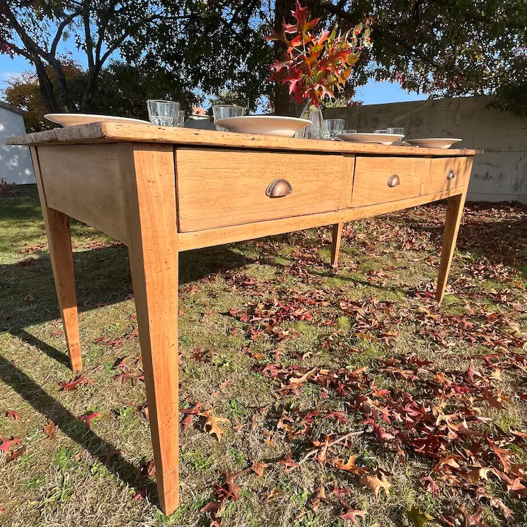 table de ferme présentée avec de la vaisselle ancienne dans le jardin