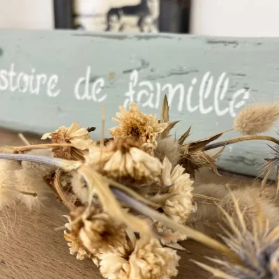 gros plan d'une pancarte en bois sur laquelle est inscrit une histoire de famille. Fleurs séchées au premier plan